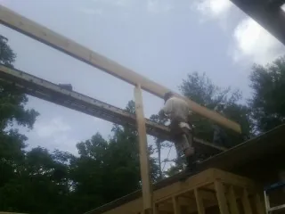 Carpenter setting a ridge beam over a new addition frame — Ice Dam Removal by Roofing Brothers in Ferris