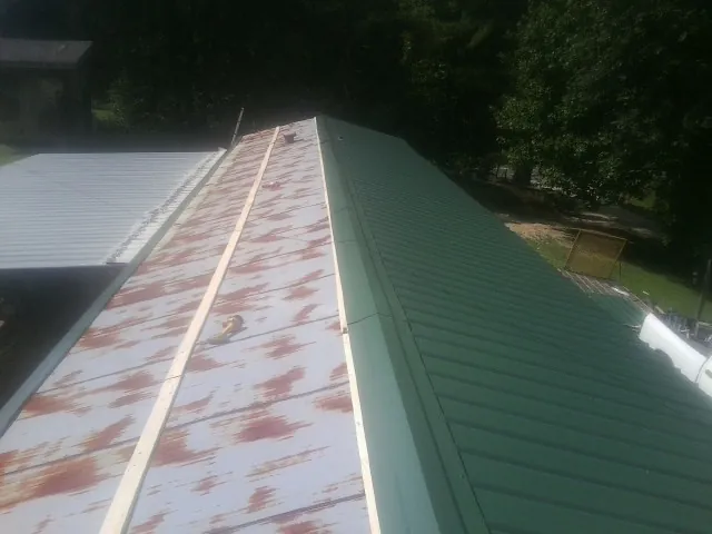 Old rusted panels beside newly installed green metal roofing — Wind Damage Roof Repair by Roofing Brothers in Ferris